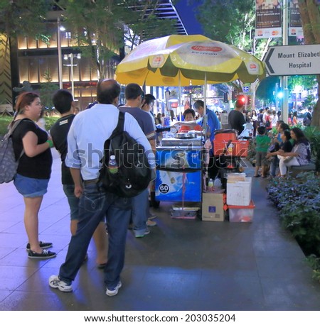 SINGAPORE - 26 May, 2014: identified people buy ice-cream on Orchard Road by night. Orchard Road is a 2.2km long boulevard that is the retail and entertainment hub of Singapore.