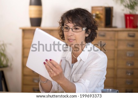 a middle-aged woman using a  computer tablet in her kitchen