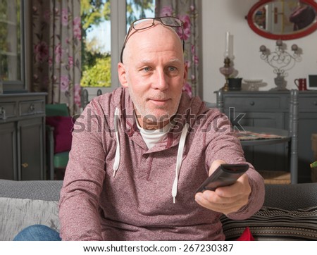 senior on a sofa in his home watch TV