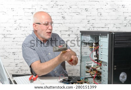 an angry man destroy his computer with a hammer