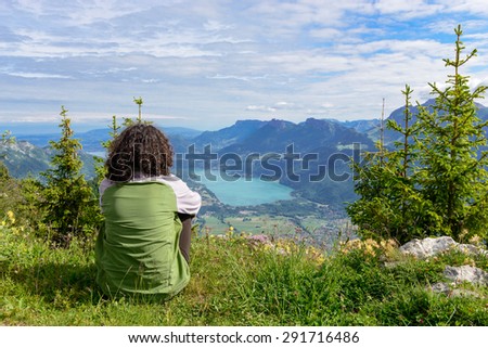 woman sitting on cliff and  looking at landscape