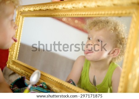 a little child sticking his tongue in the mirror