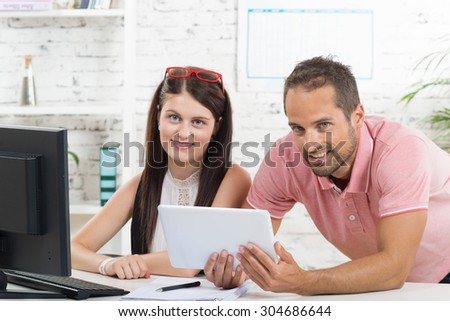 a young executive and his secretary looking at a digital tablet