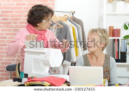 Two cheerful seamstresses working together in their fashion workshop