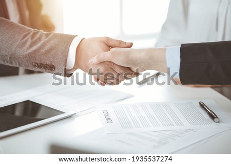 Business people shaking hands finishing contract signing in sunny office, close-up. Handshake and marketing