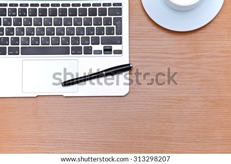 Office table with laptop, notepad and coffee cup. View from above with copy space