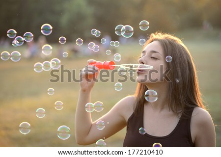 Beautiful Young Woman Blowing Bubbles Outside