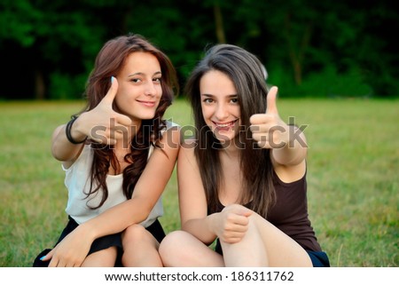Two beautiful young women giving thumbs up sign and smiling