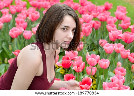 Portrait of a beautiful young woman in a pink tulip garden