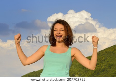 Beautiful happy woman enjoying summer outdoors and expressing success