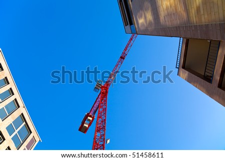 Construction site with a red crane and two buildings. Copyspace.