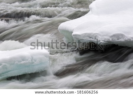 Snow and floes with icicles in fast running water