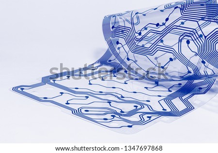 Electronic flex circuit board. Clear membrane of dismantled computer keyboard. Silicone sheet. PCB detail curled to a roll. Artistic design. Abstract bent plastic film. Blue pattern. White background. 商業照片 © 