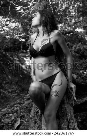 Fashion female model in bikini and painting tatoo in wild scene in rain forest