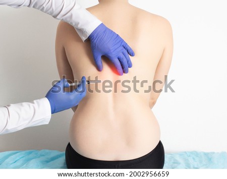 The doctor injects an ozone-oxygen mixture into the back of a girl to a patient to treat diseases of the spine and relax the muscles of the back. Modern method of ozone therapy