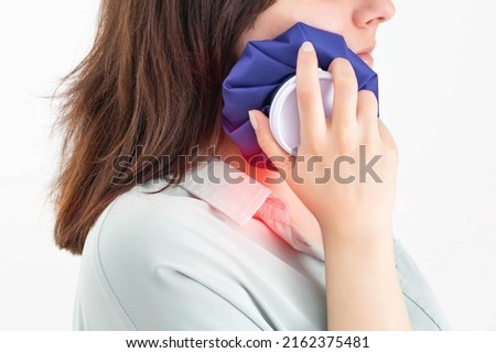 A girl attaches a medical bag with cold to the swelling on her cheek after removing a wisdom tooth. Concept for pain relief and inflammation in dentistry with the help of cold, pulpitis Stockfoto © 