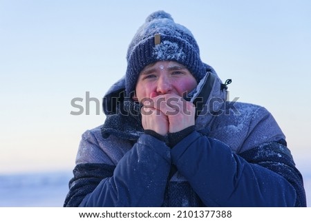 Portrait of frozen suffering guy, young handsome freezing man standing walking outdoors at winter snowy cold frosty day, shaking, trembling, shivering because of extreme low temperature in jacket, hat Foto stock © 