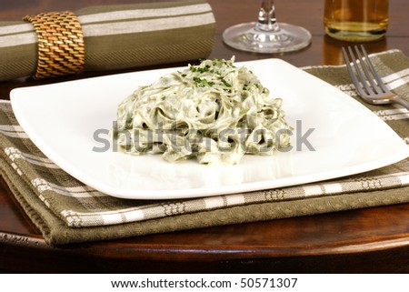 Gourmet exquisite spinach fettuccine alfredo pasta on fancy dinner table