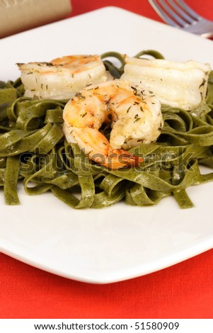 Gourmet exquisite spinach fettuccine pasta with prawns on fancy dinner table