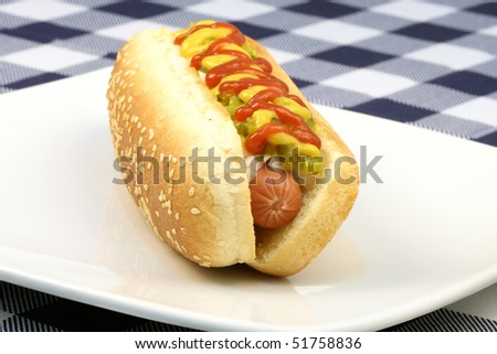 hot dog against white background with onions, pickles,ketchup and mustard on top