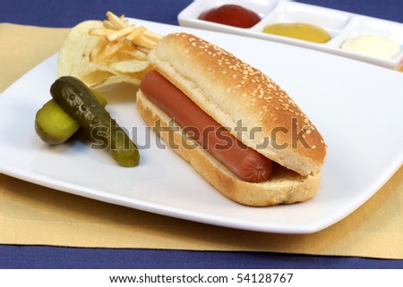 hot dog served on a white plate over fine linen with topping on the side