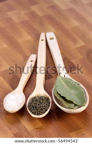 fancy wood spoons on fine wood cutting board with bay leaf ,coarse salt and ground pepper  great cooking ingredients