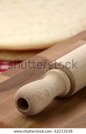pizza  dough sheeet on wood cutting board with rolling pin