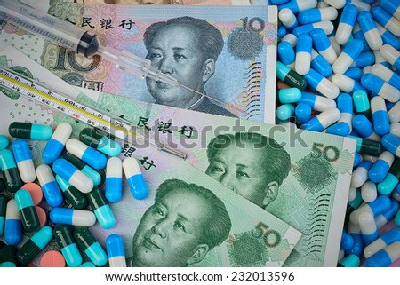thermometer,syringe and pills  on Yuan banknotes (renminbi), for costs of medications and health insurance concept ; selective focus  with vignette filter.
