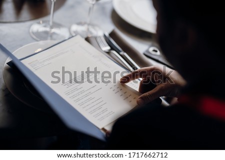 
Viewing the menu in the restaurant. Food menu. Man see the food menu. 
Order food through the menu. 