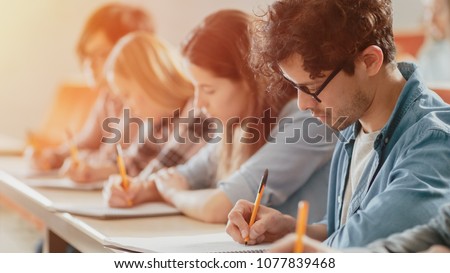 Moving Footage of a Row of Multi Ethnic Students in the Classroom Taking Exam/ Test. Focus on Holding Pens and Writing in Notebooks. Bright Young People Study at University. Foto stock © 