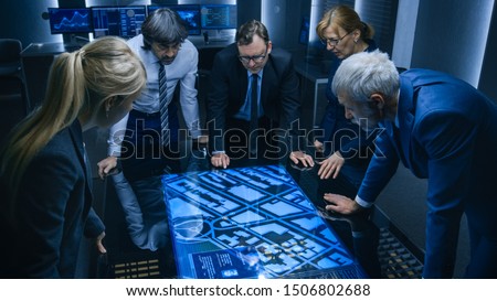 High Angle Shot of Team of Government Intelligence Agents Talking while Standing Around Digital Touch Screen Table and Tracking Suspect. Satellite Surveillance Operation in the Monitoring Room. Zdjęcia stock © 