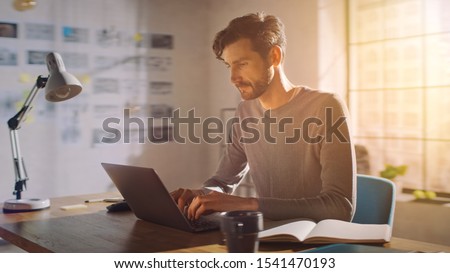 Professional Creative Man Sitting at His Desk in Home Office Studio Working on a Laptop, Concentrated Man Using Notebook Computer. ストックフォト © 