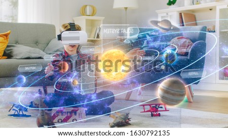 Smart Little Boy Wearing Virtual Reality Headset and Looking at Our Digitally Generated Solar System with Sun and Planets. Space Exploration with AR Glasses. He's Sitting on Carpet in His Living Room.