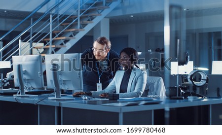 Electronics Development Engineer Working on Computer, Talks with Project Manager. Team of Professionals Use Machine Learning and Neural Networks forr the Modern Industiral Engineering Design. Stock fotó © 
