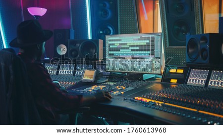 Portrait of Audio Engineer Working in Music Recording Studio, Uses Mixing Board Create Modern Sound. Successful Black Artist Musician Working at Control Desk. 商業照片 © 