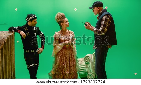 On Period Costume Drama Film Set: Beautiful Smiling Actress Wearing Renaissance Dress and Actor Wearing Motion Capture Suit Listen to Movie Director Explaining to Her Scene Context.