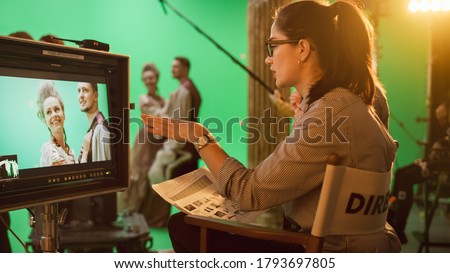 Famous Talented Female Director in Chair Looks at Display Following Shootings of a New Blockbuster. Green Screen Scene in Historical Drama. Film Studio Set Professional Crew Doing High Budget Movie