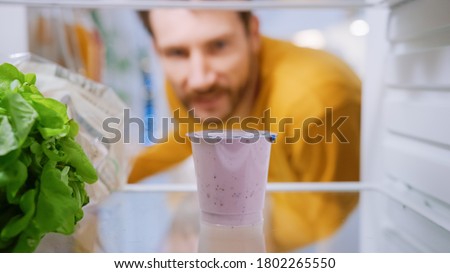 Camera Inside Kitchen Fridge: Handsome Man Opens Fridge Door, Thinks to Takes out Yogurt. Man Eating Healthy. Point of View POV Shot from Refrigerator full of Healthy Food