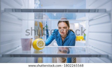 Dissappointed and Angry Young Woman Looks inside the Fridge, Checks Out that it's Empy. Point of View POV from Inside of the Kitchen Refrigerator