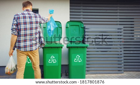 Caucasian Man is Throwing Away Two Plastic Bags of Trash next to His House. One Garbage Bag is Sorted with Biological Food Waste, Other with Recyclable Bottles Garbage Bin. Stockfoto © 