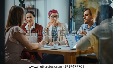 Office Meeting in Conference Room: Beautiful Specialist with Short Pink Hair Talks about Firm Strategy with Diverse Team of Professional Businesspeople. Creative Start-up Team Discusses Big Project