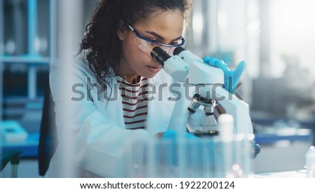 Medical Science Laboratory: Portrait of Beautiful Black Scientist Looking Under Microscope Does Analysis of Test Sample. Ambitious Young Biotechnology Specialist, working with Advanced Equipment