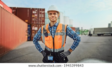 Portrait of a Handsome Caucasian Industrial Engineer in White Hard Hat, Orange High-Visibility Vest, Checkered Shirt, Jeans and Work Gloves. Foreman or Supervisor Has a Two-Way Radio Attached. Stockfoto © 