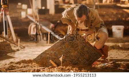 Archaeological Digging Site: Great Male Archeologist Work on Excavation Site, Carefully Cleaning, Lifting Newly Discovered Ancient Civilization Cultural Artifact, Historic Clay Tablet, Fossil Remains Сток-фото © 