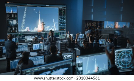 Group of People in Mission Control Center Witness Successful Space Rocket Launch. Flight Control Employees Sit in Front Computer Displays and Monitor the Crewed Mission. Team Stand Up and Clap Hands.