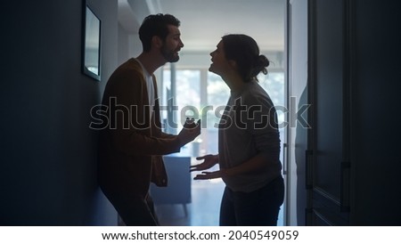 Young Couple Arguing and Fighting. Domestic Violence and Emotional abuse Scene, Stressed Woman and aggressive Man Screaming at Each other in the Dark Hallway of Apartment. Dramatic Scene Foto stock © 