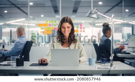 Young Happy Businesswoman Using Computer in Modern Office with Colleagues. Stylish Beautiful Manager Smiling, Working on Financial and Marketing Projects. Drinking Tea or Coffee from a Mug. Foto stock © 