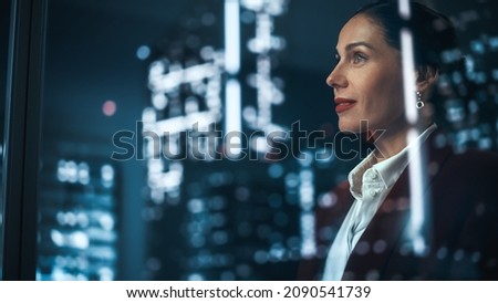 Successful Businesswoman in Stylish Suit Working on Top Floor Office Overlooking Night City. High Achievement Female CEO of Humanitarian Investment Fund, Human Face of Sustainable Corporate Governance 商業照片 © 