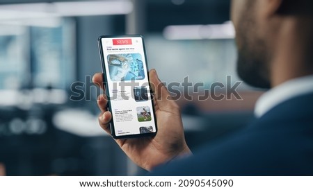 Foto Bild Schwarzer Geschäftsmann mit einem Smartphone in der Nähe eines Bürogebäudes