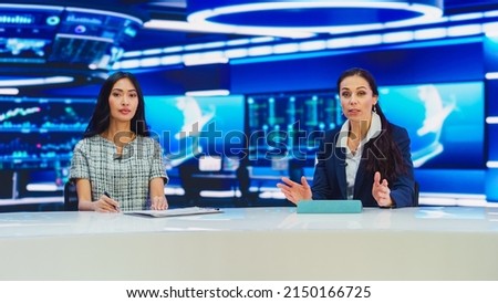 TV Live News Program: Two Presenters Reporting, Discuss Daily Events, Discuss Business, Economy, Science, Entertainment. Television Cable Channel Diverse Anchors Talk. Playback Newsroom Studio Foto stock © 